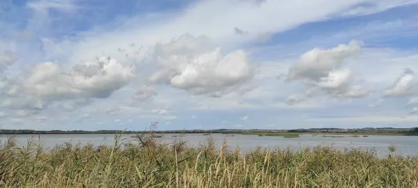Göl, mavi gökyüzü ve bulutların arka planında