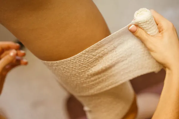 Meisje bindt haar been in een wit verband Rechtenvrije Stockafbeeldingen
