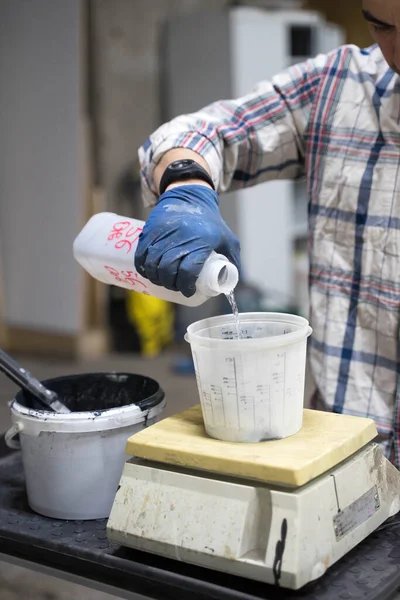 Мужчина наливает краску в пластиковую банку — стоковое фото