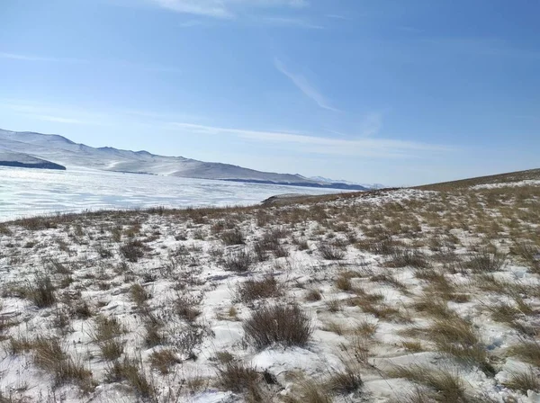 Bevroren meer met transparant ijs op een blauwe lucht achtergrond — Stockfoto