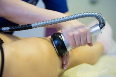 Kadın masaj cihazıyla ayak masajı yapıyor.