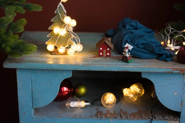 A little christmas tree stands on a table with lights — Foto Stock