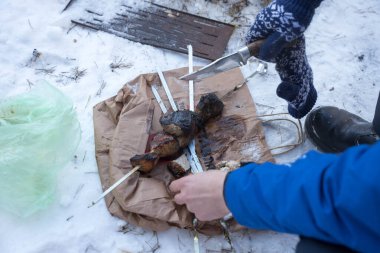 man removes kebabs from a skewer in winter