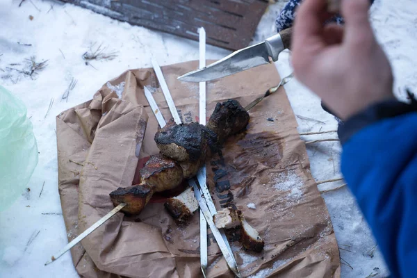Man removes kebabs from a skewer in winter — 图库照片