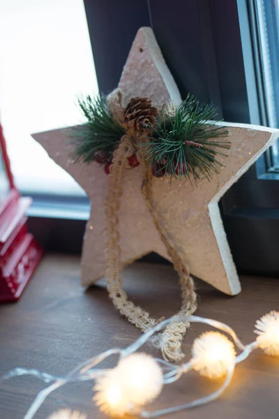 Christmas star stands on the windowsill with lights in a garland — Foto Stock