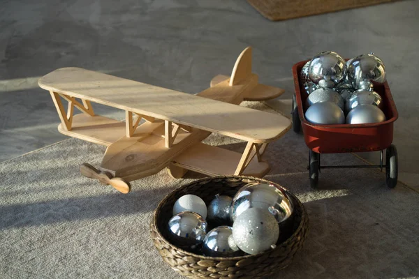 Een houten vliegtuig ligt op een tapijt met grote kerstboom speelgoed — Stockfoto