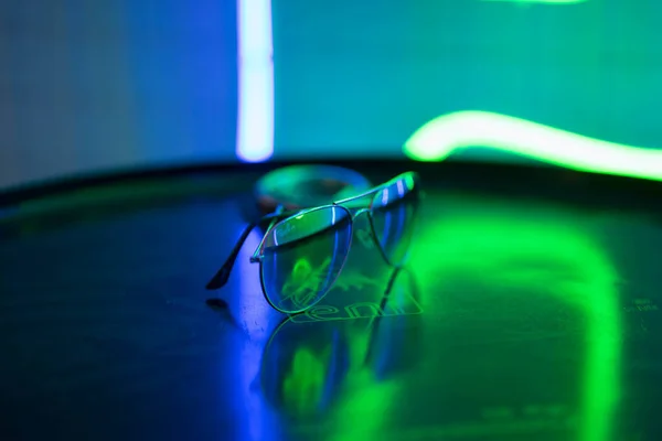 Солнцезащитные очки лежат на круглой поверхности и отражают неоновый свет — стоковое фото