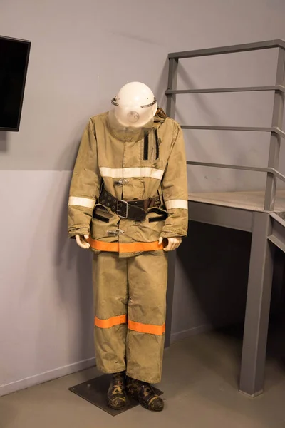 Um terno de bombeiro com um capacete fica ao lado das escadas — Fotografia de Stock