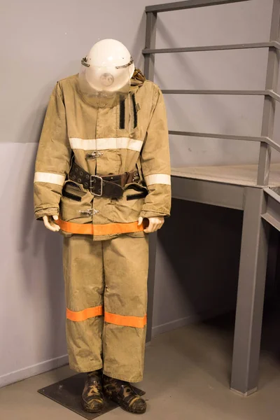 Um terno de bombeiro com um capacete fica ao lado das escadas — Fotografia de Stock