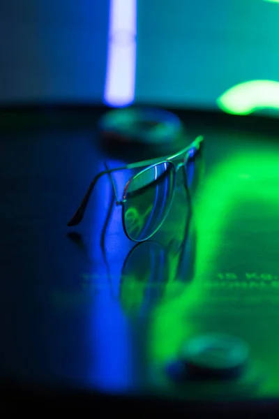 Sluneční Brýle Leží Kulatém Povrchu Jiskří Neonově Modrozelených Světlech — Stock fotografie