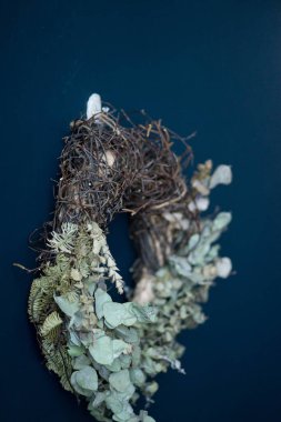 Mavi bir duvarda çelenk asılı.