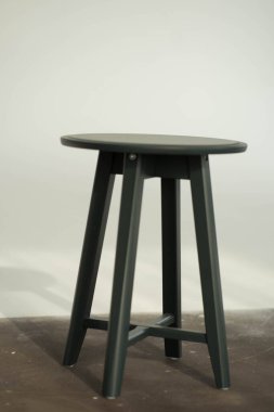 Bacakları beyaz bir duvarda duran yuvarlak bir sandalye.