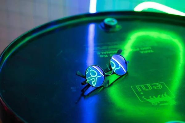 Sluneční Brýle Leží Železném Povrchu Odrážejí Neonově Modrozeleném Světle — Stock fotografie