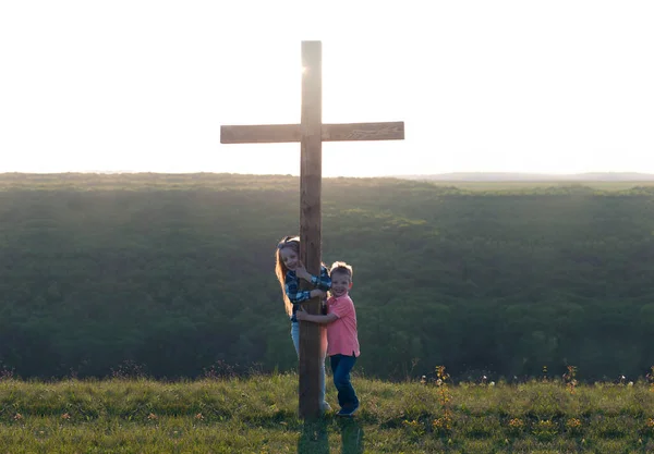Wooden cross. Crucifixion on the background of the sky. Children near the cross. Repentance and forgiveness