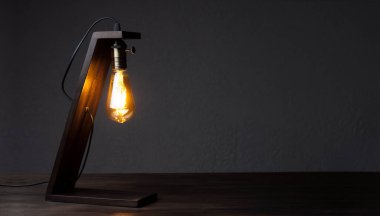 Masa lambası masanın üzerinde. Ahşap dekoratif lamba Edison. Karanlıkta gece ışığı.