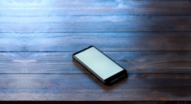 Telefonunuz var. Beyaz ve boş ekranlı bir telefon. Tahta bir masada..
