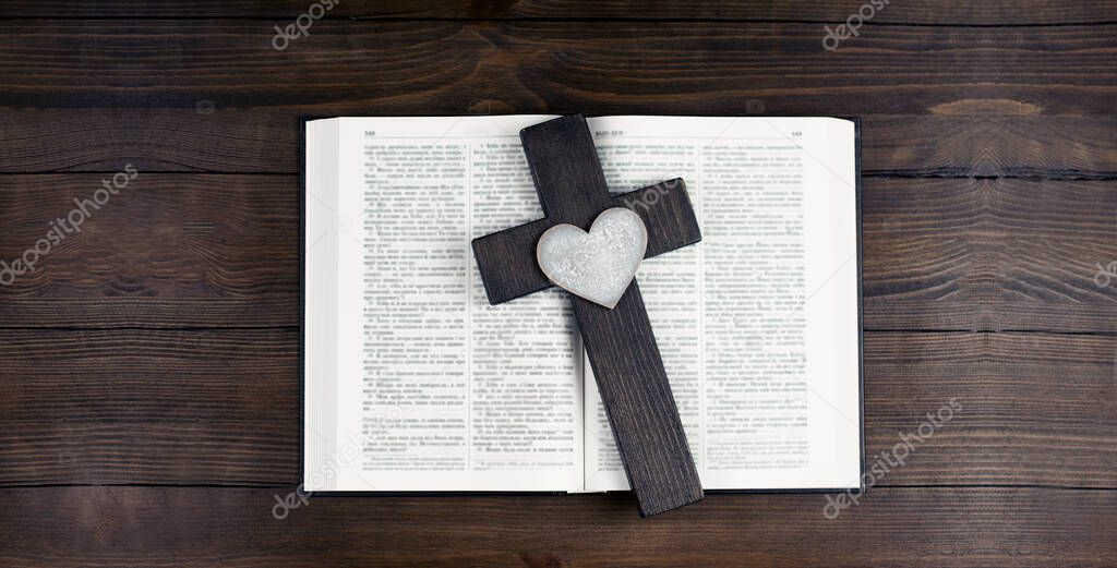 Open Bible.. Opened holy bible books on the table. Scripture. Cross of Jesus. Heart. On a wooden background