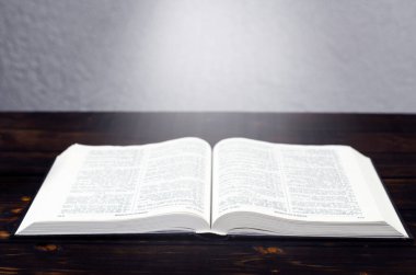 İncil 'i aç, tahta bir masanın üzerinde. Masa lambası. Bir kitaptan ışık