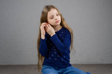 Kız yerde oturuyordur. Kız küpe takıyor. Avrupa.