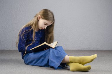 Kız yerde oturuyordur. Kitap oku. Avrupa.