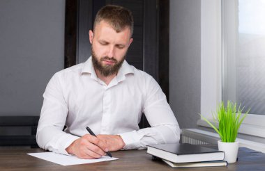 Young businessman is sitting at the table. A man in a shirt. Office worker.