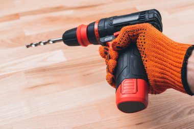 Tornavida ustasının elinde matkap. Eller iş eldiveninde..