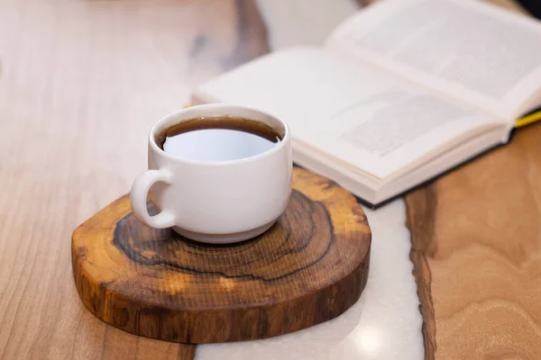 A cup of coffee and a book on the table.