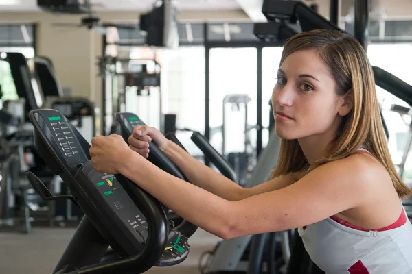 Femme exerçant sur le cycle stationnaire — Photo