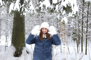 Beyaz şapkalı, eldivenli, mavi ceketli, karlı bir kadın.