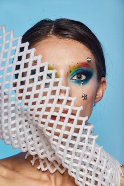 Moda yaratıcı makyaj. Temiz ve parlak ciltli genç bir kadının güzel portresi ve parlak mavi bir arka planda duran yapay elmaslarla süslenmiş.