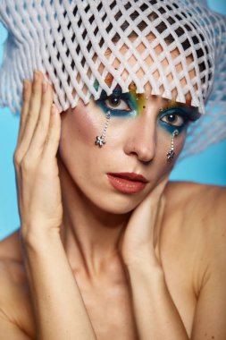 Moda yaratıcı makyaj. Temiz ve parlak ciltli genç bir kadının güzel portresi ve parlak mavi bir arka planda duran yapay elmaslarla süslenmiş.