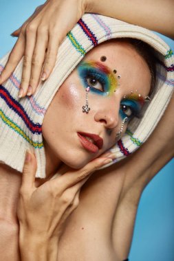 Moda yaratıcı makyaj. Temiz ve parlak ciltli genç bir kadının güzel portresi ve parlak mavi bir arka planda duran yapay elmaslarla süslenmiş.