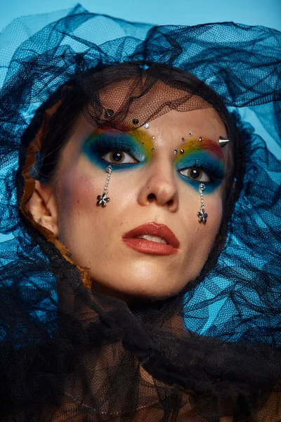 Moda yaratıcı makyaj. Temiz ve parlak ciltli genç bir kadının güzel portresi ve parlak mavi bir arka planda duran yapay elmaslarla süslenmiş.