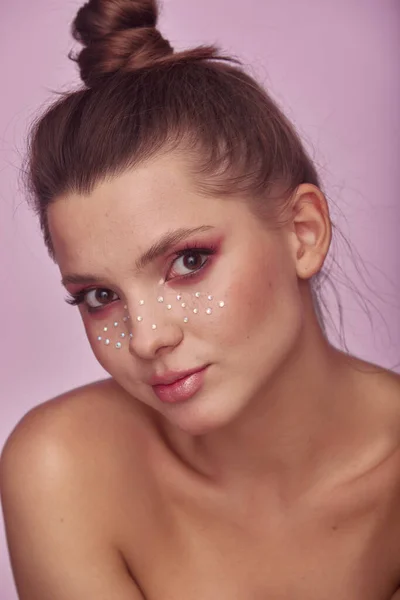 具有时尚创意的年轻女子的美丽肖像 洁白的皮肤和明亮的妆容与莱茵石雀斑在她的脸上摆出明亮的粉红色背景 — 图库照片