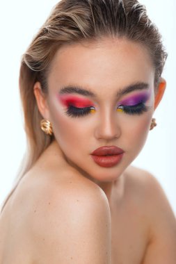 Bayan portresi. Mavi gözlü ve dolgun dudaklı bir model için profesyonel makyaj. Kırmızı ruj, renkli dumanlı gözler. Beyaz bir arkaplanda izole edilmiş.