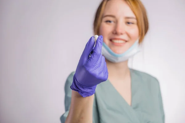 魅力的な女性歯科医を保持または歯を示し 灰色の背景に均一な医療面マスクとラテックス医療手袋を身に着けている肖像画 — ストック写真
