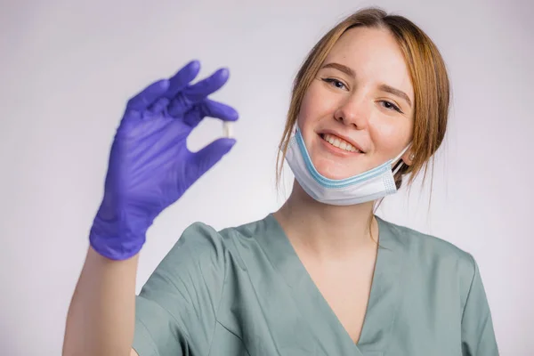 魅力的な女性歯科医を保持または歯を示し 灰色の背景に均一な医療面マスクとラテックス医療手袋を身に着けている肖像画 — ストック写真