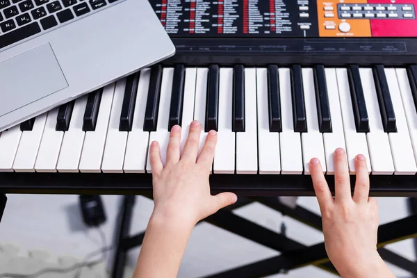 Ev müziği dersi. Şirin sarışın kız piyano çalmayı öğreniyor dizüstü bilgisayar, davul seti ve gitarı bulanık arka planda seyrediyor. Evde müzik eğitimi alıyorum.