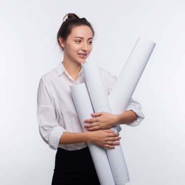 Genç ve sevimli iş kadını elinde planlar tutuyor. Projesi onaylandığı için çok mutlu ve işi beyaz fotokopi alanında izole etmiş.