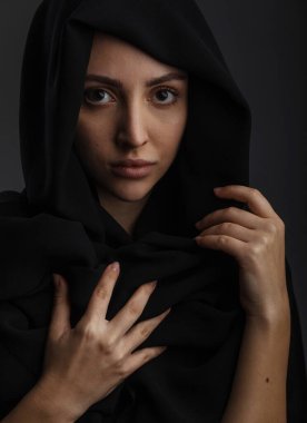 Gündelik giysiler içinde genç Müslüman kadın model ve geleneksel siyah tesettür gülümseyen ve koyu gri arka planda kameraya bakan, kopyalama alanı