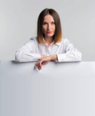 Beyaz afişi ya da planları olan Avrupalı bir iş kadını, gri arka planda karttan izole edilmiş stüdyo resmi, kopyalama alanı