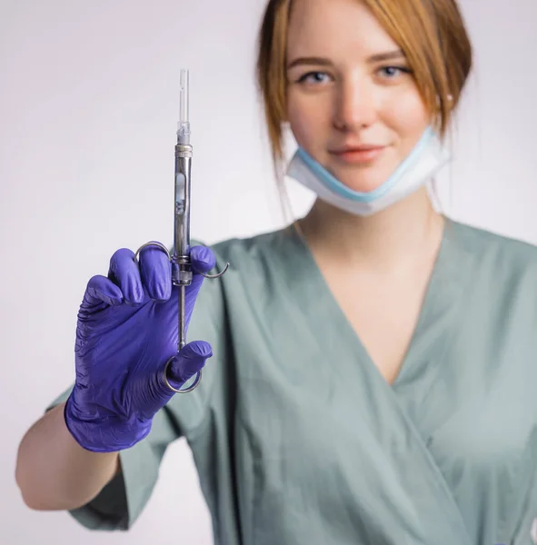 注射器を持つ魅力的な女性歯科医の肖像 灰色の背景に均一な医療面マスクとラテックス医療手袋を身に着けています — ストック写真