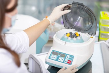 Tıbbi santrifüj. Bilim adamı tıbbi veya bilimsel laboratuardaki santrifüj makinesine örnek yüklüyor.