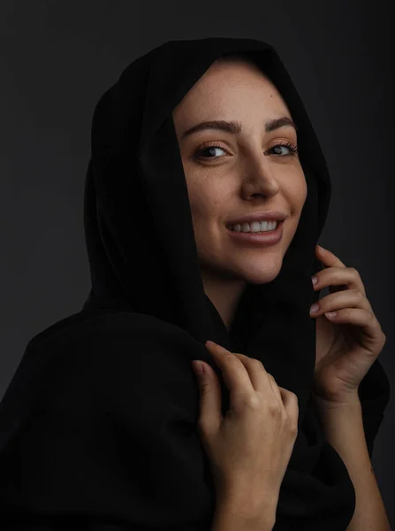 穿着休闲装的年轻穆斯林女性模特和传统的黑色头巾微笑着 在深灰色背景下看着相机 复制空间 — 图库照片