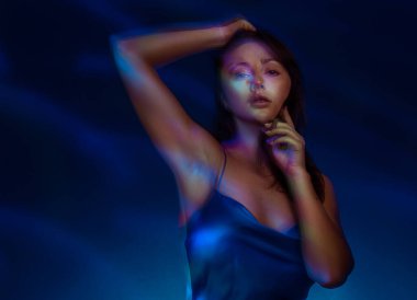 Işık boyama tarzında bir portre. Mavi elbiseli esmer kadın uzun pozlu fotoğraf, soyut portre ışığı ve dondurucu arka plan