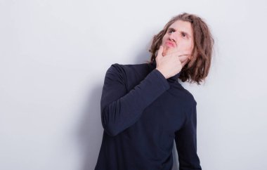 Koyu gri balıkçı yaka kazaklı komik bir adamın portresi ve gri arka plan fotokopi uzayında izole edilmiş kafasında kısa örgü.