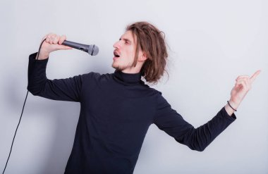 Duygusal portresi sallanan komik adam mikrofona şarkı söylüyor, arka plandaki gri fotokopi alanından izole edilmiş.