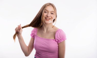 Uzun sarı saçlarını çeken tatlı bir genç kadın. Güzel bir kadın beyaz arka plan fotokopi alanında saç tutuyor. Kafa ve saç bakım ve sağlık konsepti