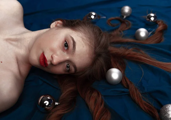 Милая Рыжая Молодая Женщина Лежит Голубой Кровати Декоративными Рождественскими Яйцами — стоковое фото