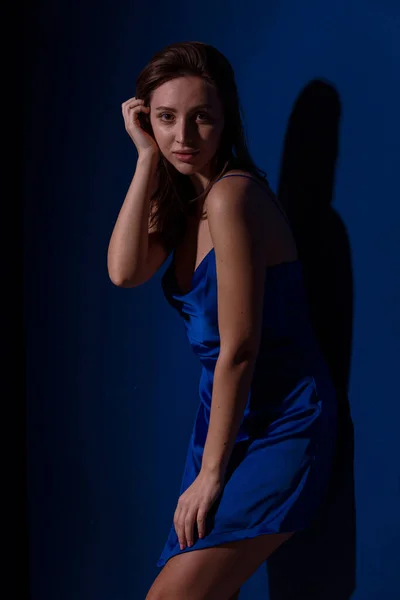 穿着浅蓝色衣服的年轻貌美的黑发女人 穿着深蓝色背景的衣服 在空旷的文字空间里摆姿势 — 图库照片